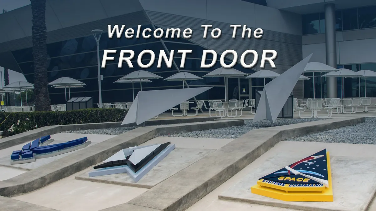Entrance plaza with a ‘Welcome to the Front Door’ sign and Space Force emblems
